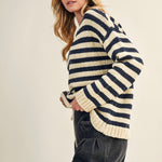 Woman wearing a striped sweater and dark jeans on a plain background