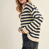 Woman wearing a striped sweater and dark jeans on a plain background