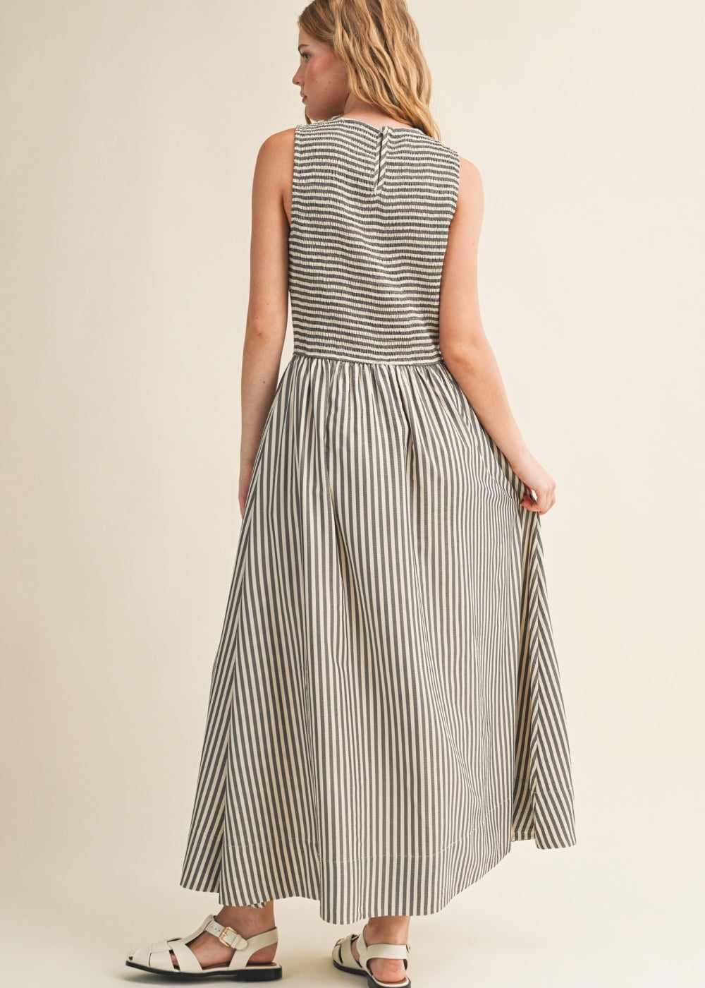 Back view of Darcy Smocked Stripe Maxi Dress in black and ivory stripe, featuring a smocked bodice, sleeveless cut, and relaxed maxi-length skirt.