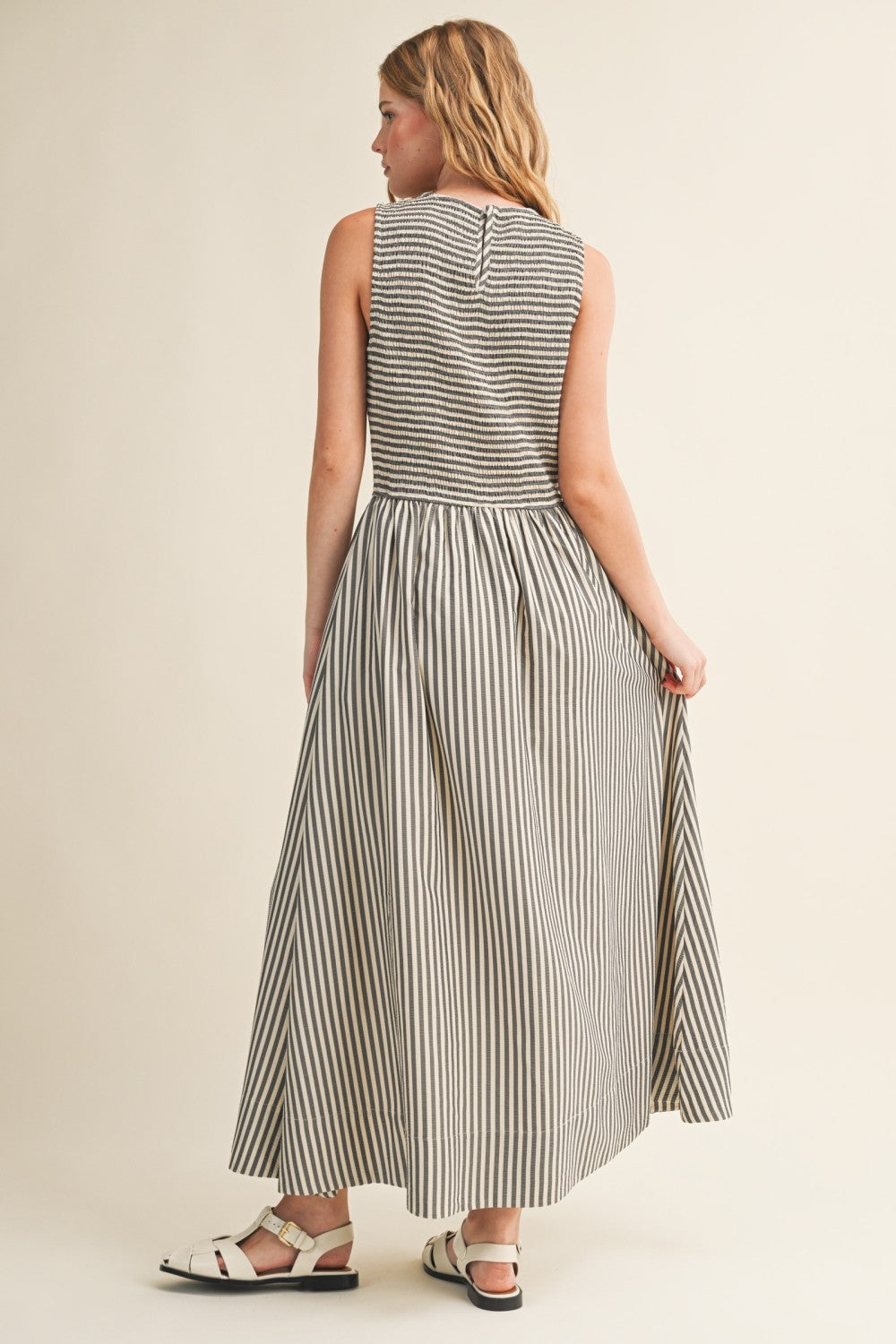 Back view of Darcy Smocked Stripe Maxi Dress in black and ivory stripe, featuring a smocked bodice, sleeveless cut, and relaxed maxi-length skirt.