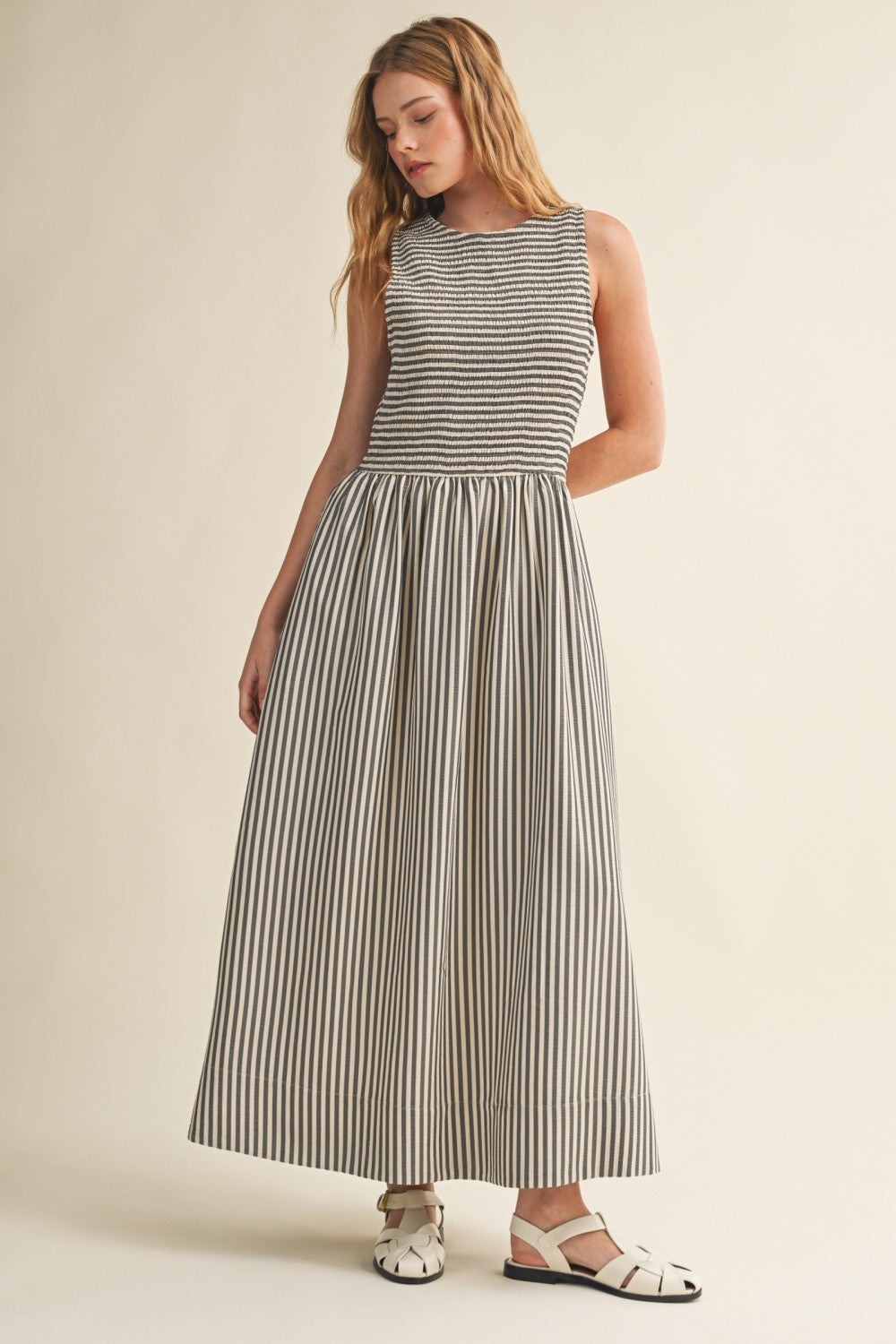 Darcy Smocked Stripe Maxi Dress in black and ivory stripe, full-length front view with sleeveless smocked bodice and side pockets.