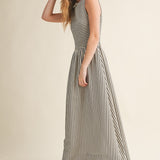 Side view of Darcy Smocked Stripe Maxi Dress in black and ivory stripe with sleeveless smocked bodice, flowing maxi skirt, and side pockets.