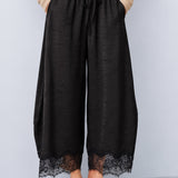 Front view of Daydream black lace-trim satin barrel pants styled with a beige top and ballet flats