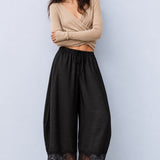Model wearing Daydream black satin barrel pants with a beige sleeveless top and ballet flats