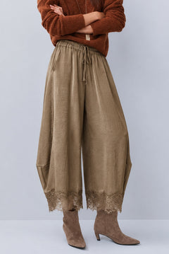 Front view of Daydream olive lace-trim satin barrel pants styled with a brown top and heels