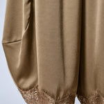Close-up of the olive satin fabric and delicate lace-trimmed hems on Daydream barrel pants
