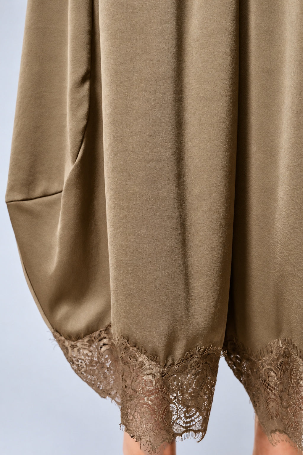 Close-up of the olive satin fabric and delicate lace-trimmed hems on Daydream barrel pants