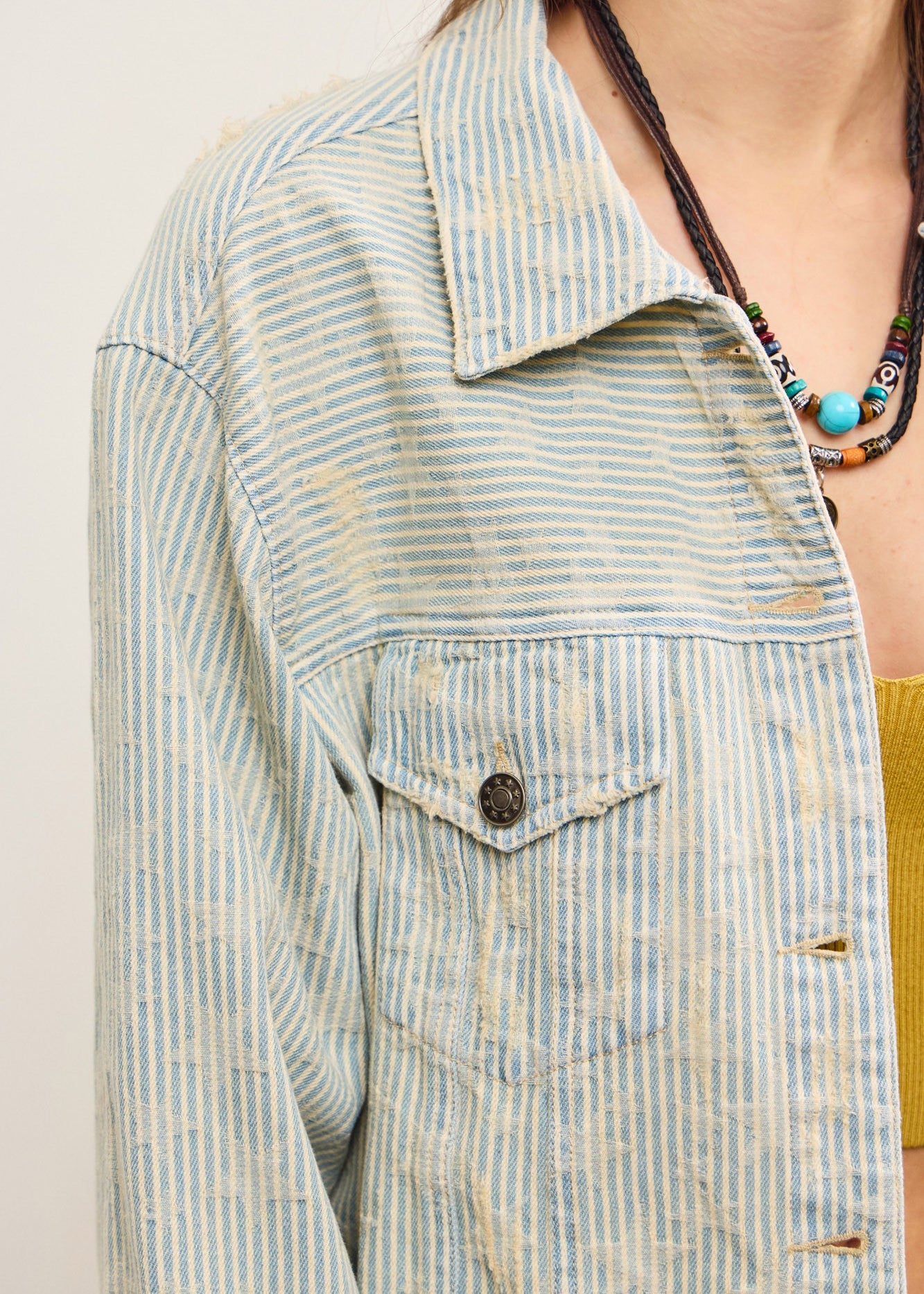 Close-up of striped denim fabric on distressed hem jacket in sand wash