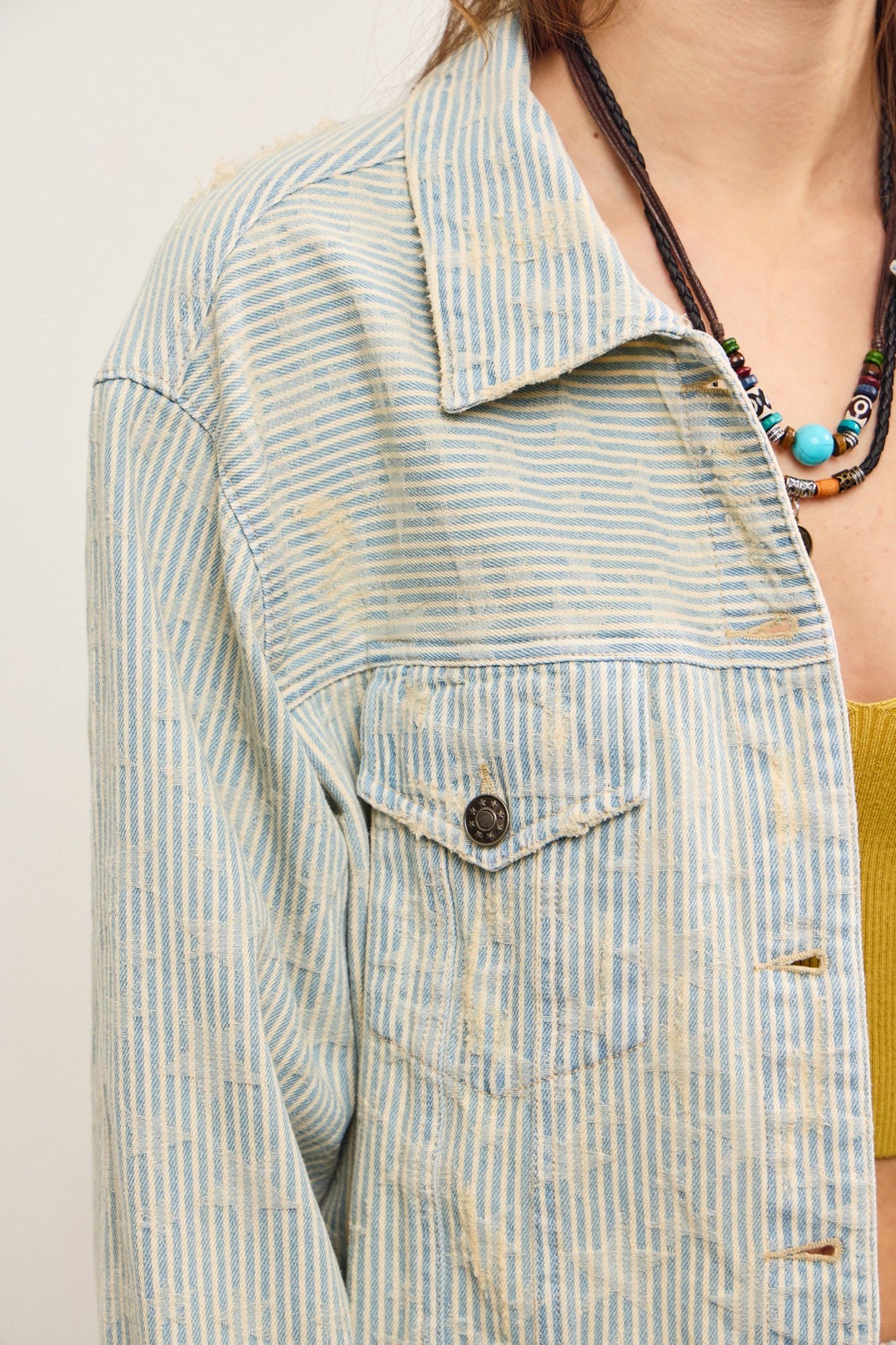 Close-up of striped denim fabric on distressed hem jacket in sand wash