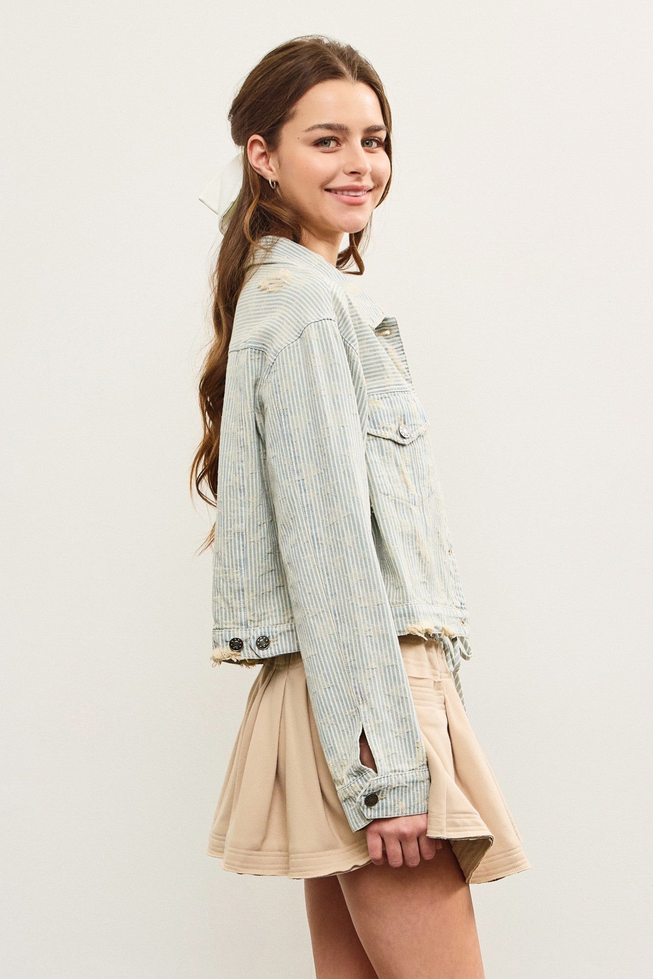 Side view of distressed hem striped denim jacket showing cropped length