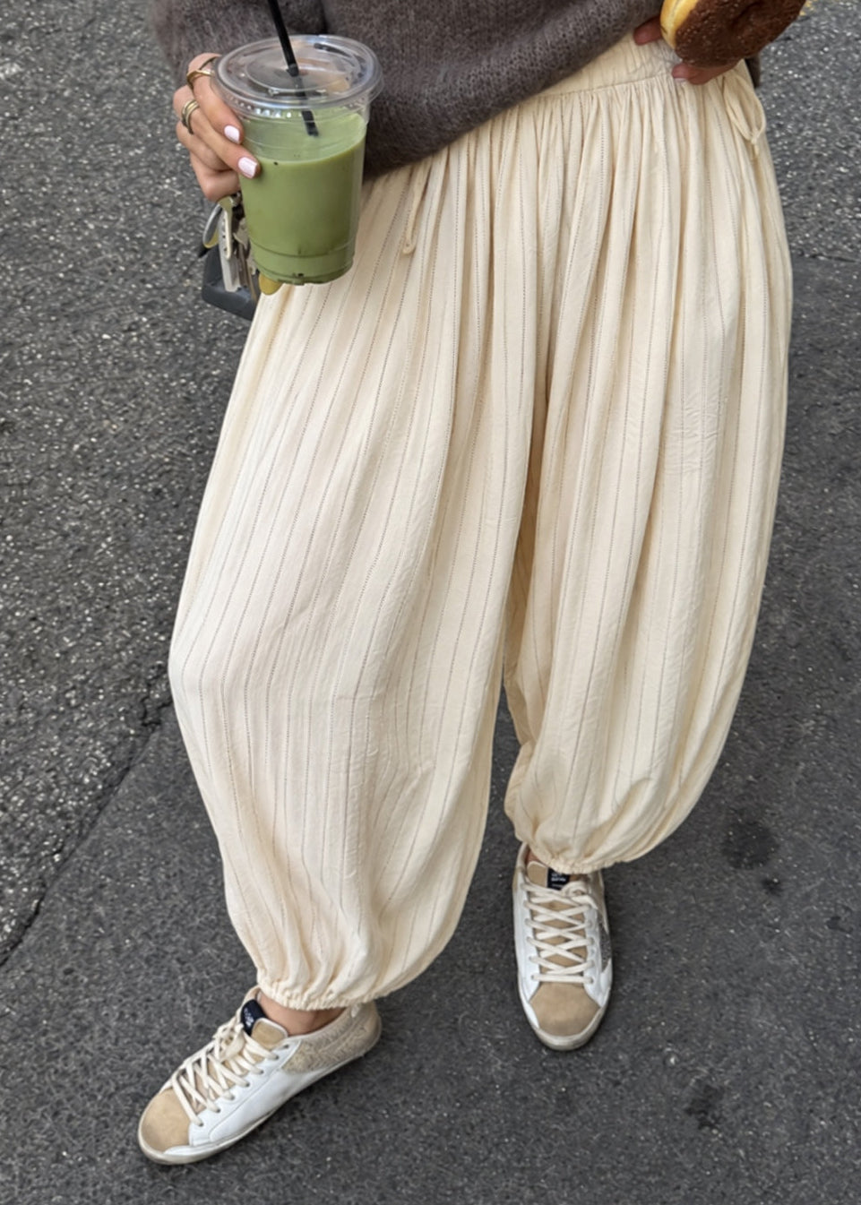 Woman styling the Double Bubble striped satin balloon pants in beige