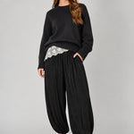 Front view of women’s black striped satin balloon harem pants with a relaxed bubble-leg shape