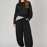 Front view of women’s black striped satin balloon harem pants with a relaxed bubble-leg shape