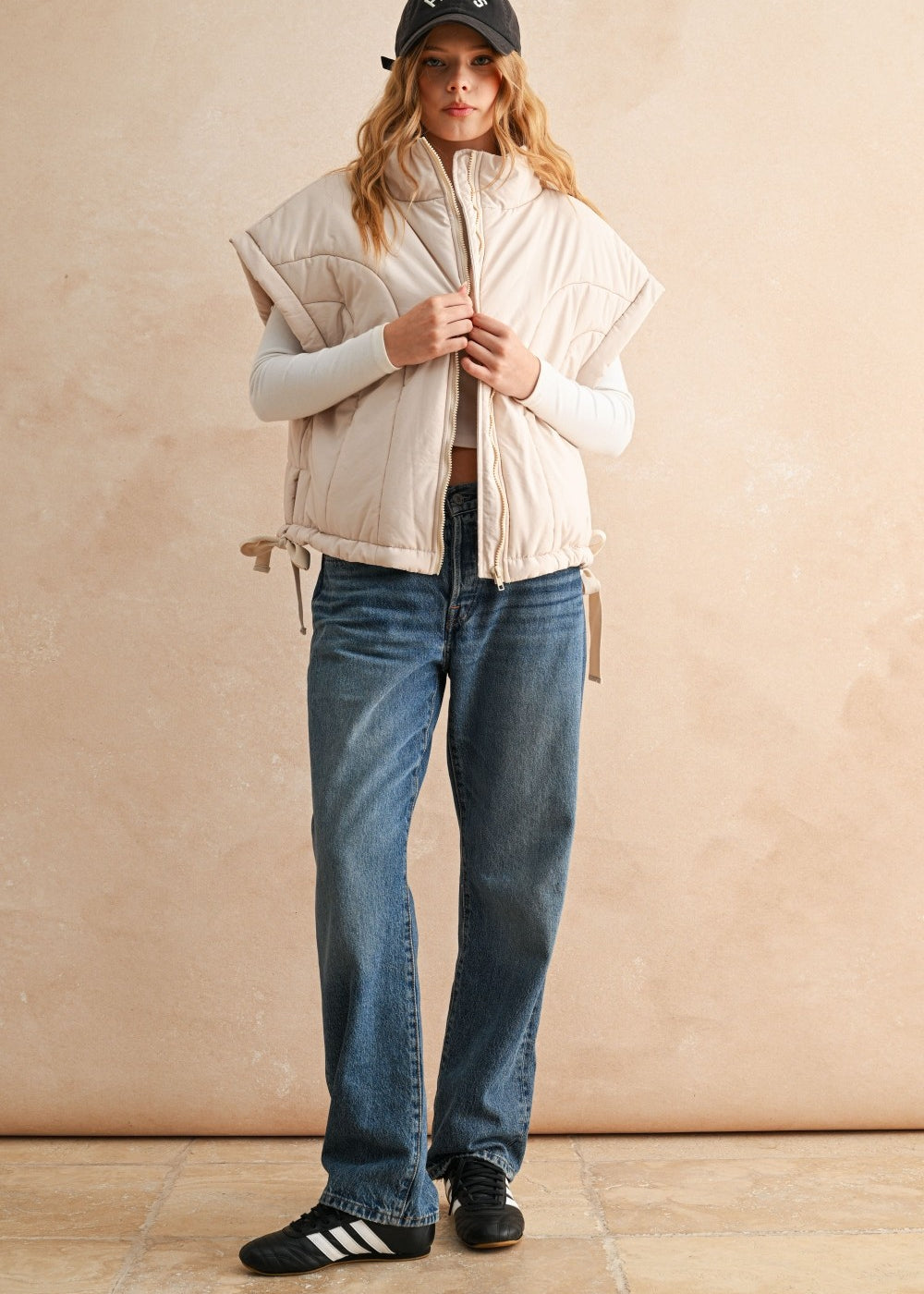 Ecru puffer vest layered over knit sweater and jeans — casual women’s layering outfit for cool weather.