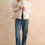 Ecru puffer vest layered over knit sweater and jeans — casual women’s layering outfit for cool weather.