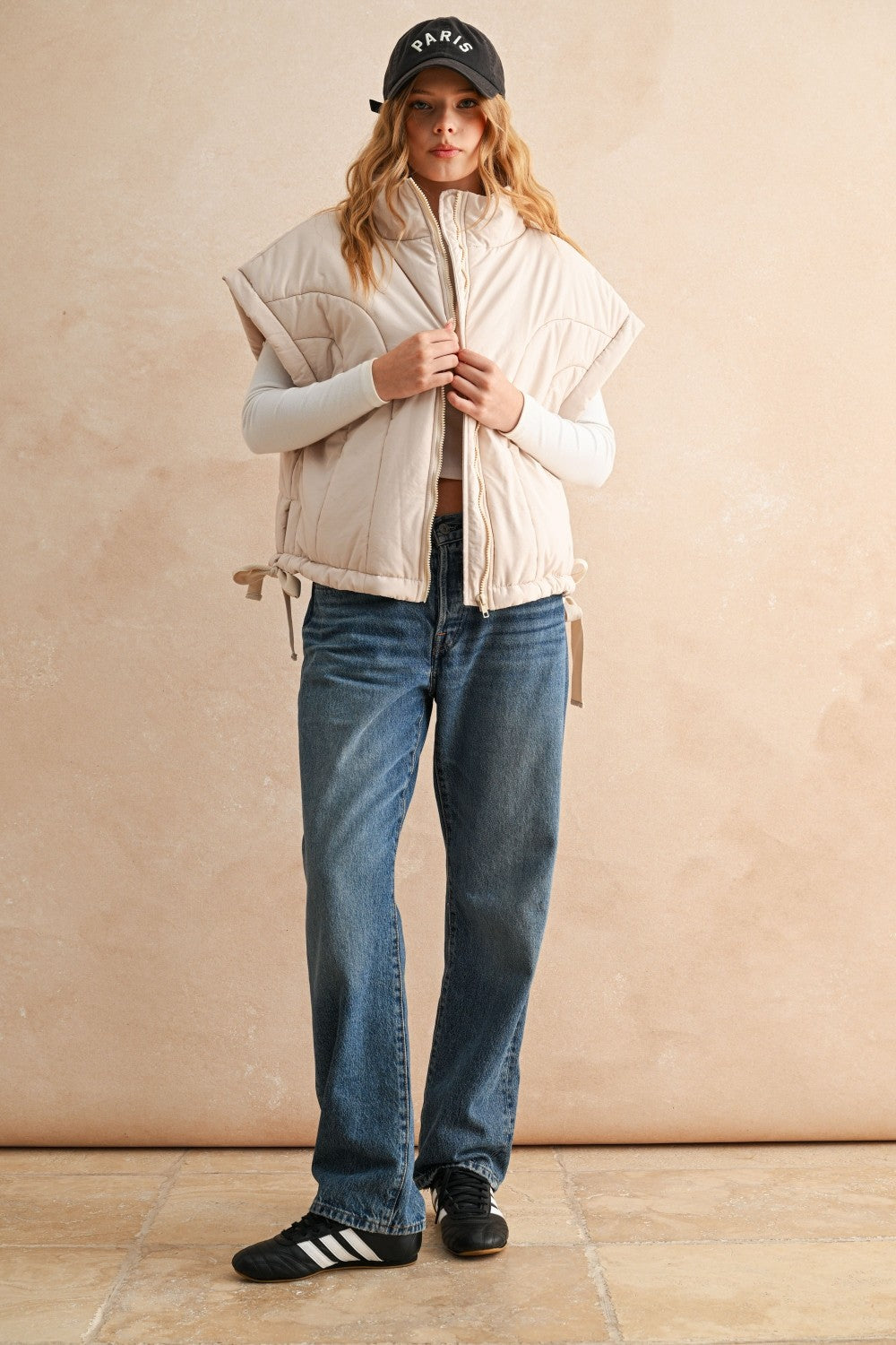 Ecru puffer vest layered over knit sweater and jeans — casual women’s layering outfit for cool weather.