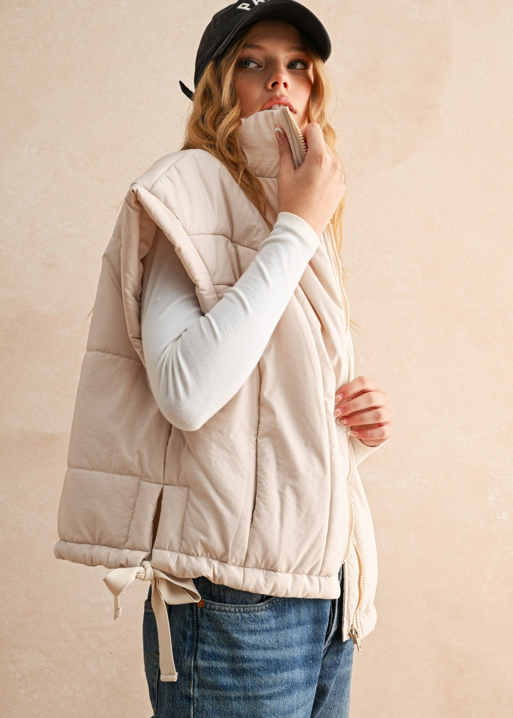 Side view of ecru bubble puffer vest showing high neckline, adjustable hem, and lightweight design.