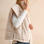 Side view of ecru bubble puffer vest showing high neckline, adjustable hem, and lightweight design.