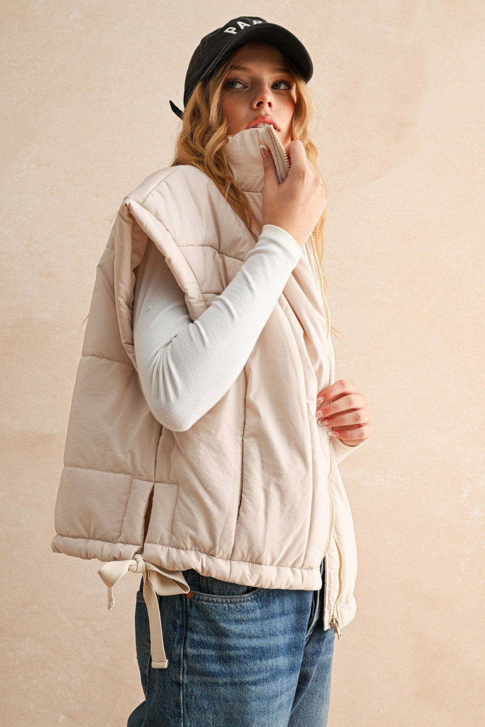 Side view of ecru bubble puffer vest showing high neckline, adjustable hem, and lightweight design.