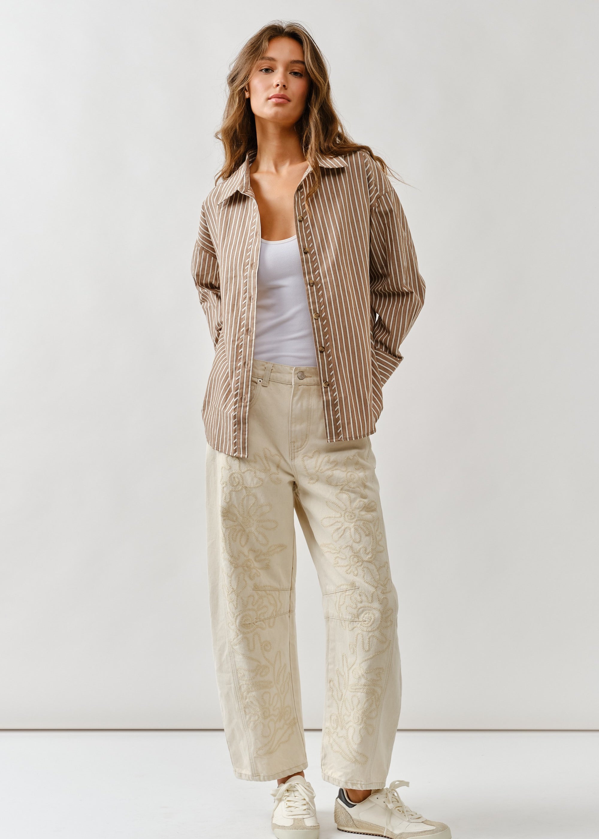 Front lifestyle view of model wearing Floral Embroidered Barrel Leg Jeans in beige