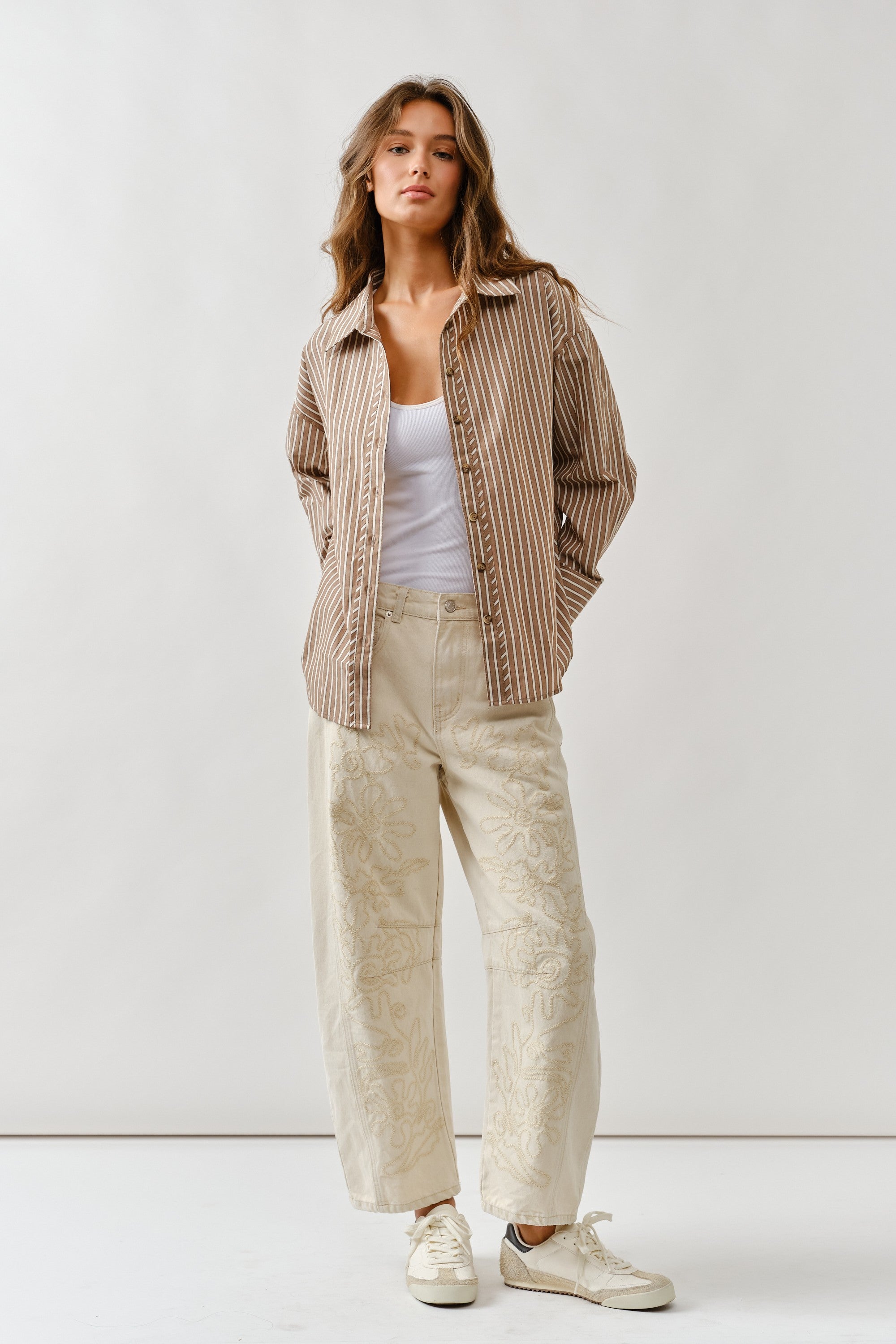 Front lifestyle view of model wearing Floral Embroidered Barrel Leg Jeans in beige