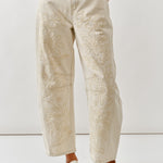 Person wearing beige embroidered pants on a white background