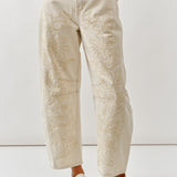 Person wearing beige embroidered pants on a white background