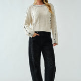 Woman wearing a white ribbed sweater and black jeans against a white background