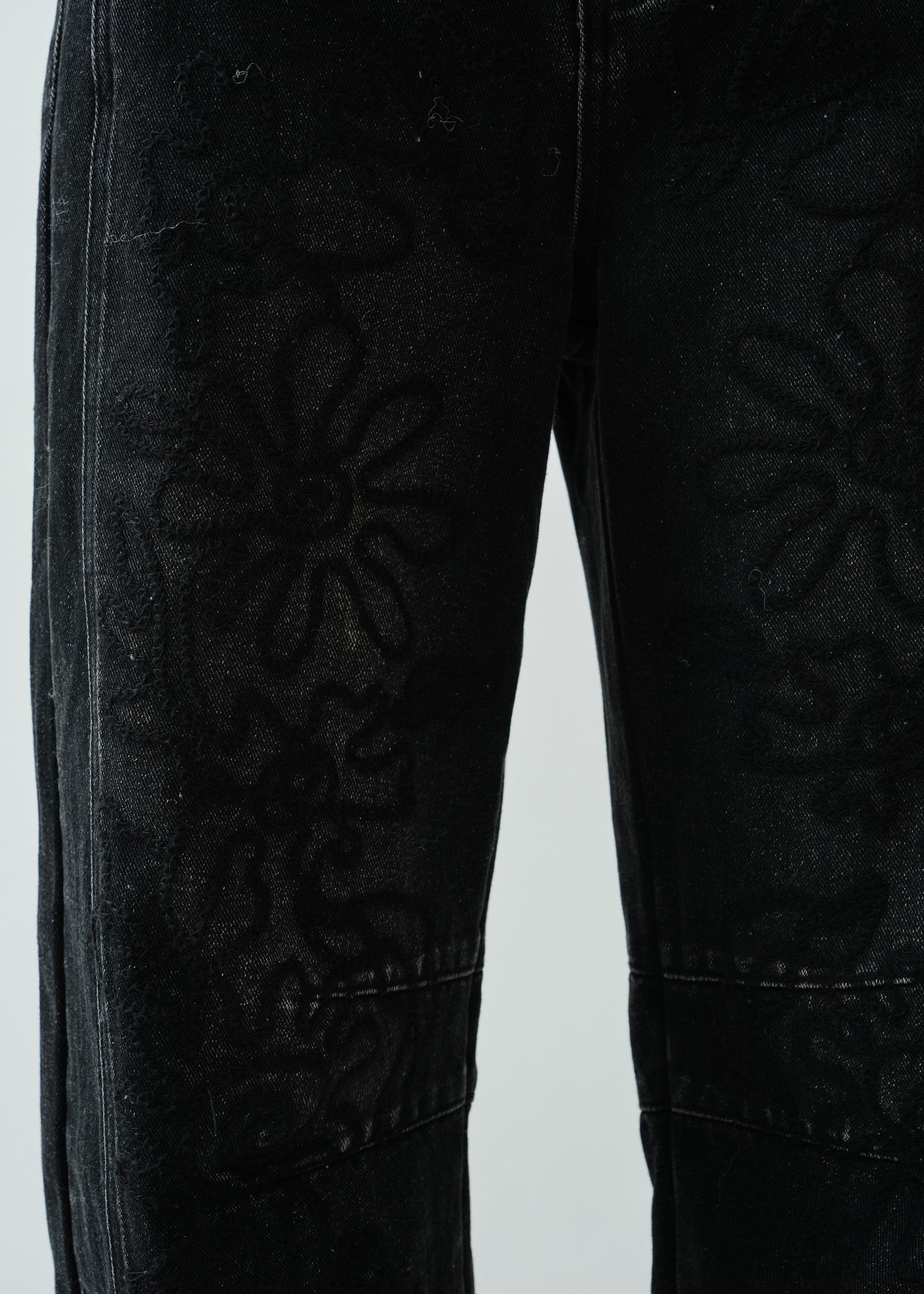 Close-up detail of the barrel-leg shape and faded black denim texture