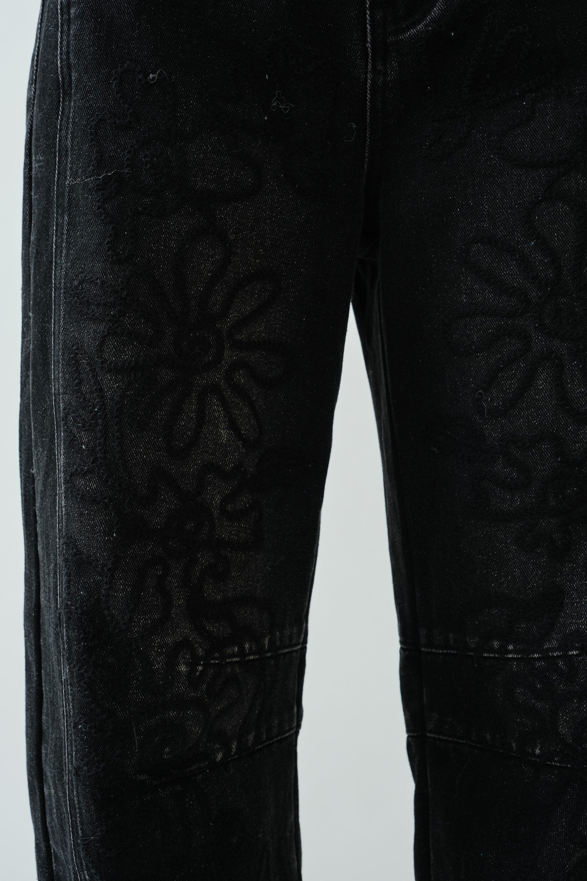 Close-up detail of the barrel-leg shape and faded black denim texture