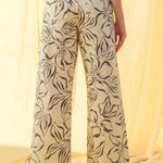 Back view of charcoal floral print wide leg denim pants with high-rise fit and raw hem