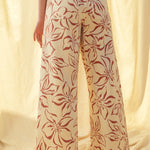 Back view of red floral print wide leg denim pants with relaxed fit and raw hem