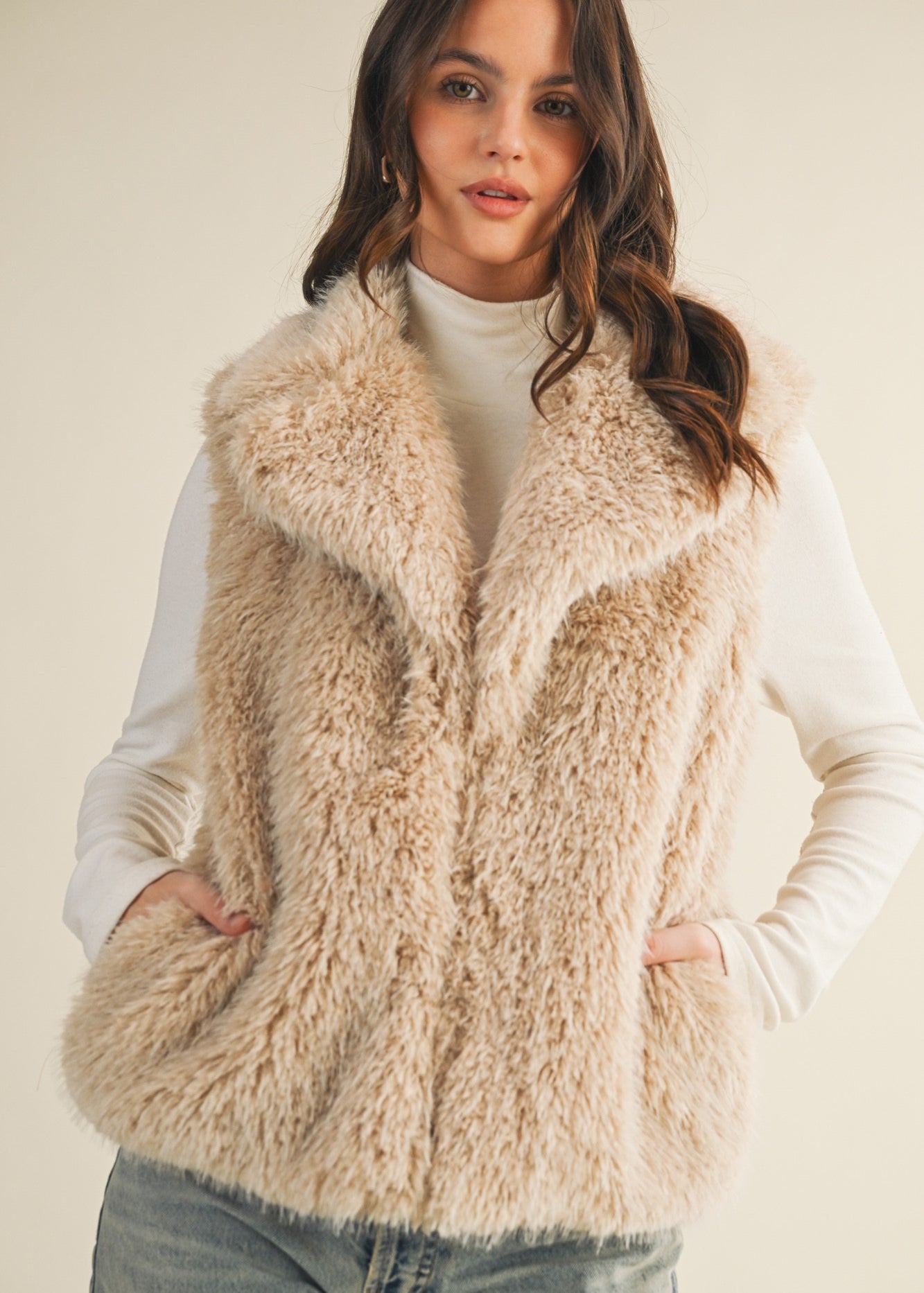 Styled front view of the faux fur vest layered over a knit top