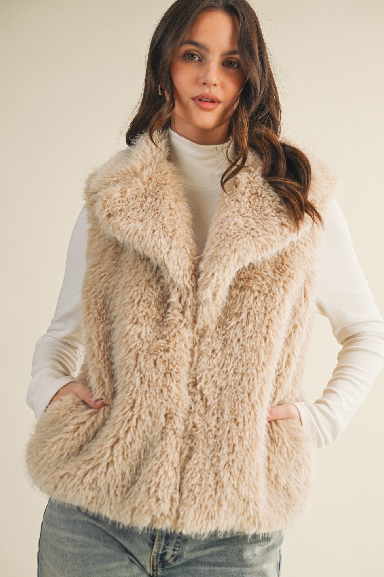 Styled front view of the faux fur vest layered over a knit top