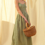 Woman in a Smocked cotton gingham maxi dress in green with spaghetti straps and flowing skirt