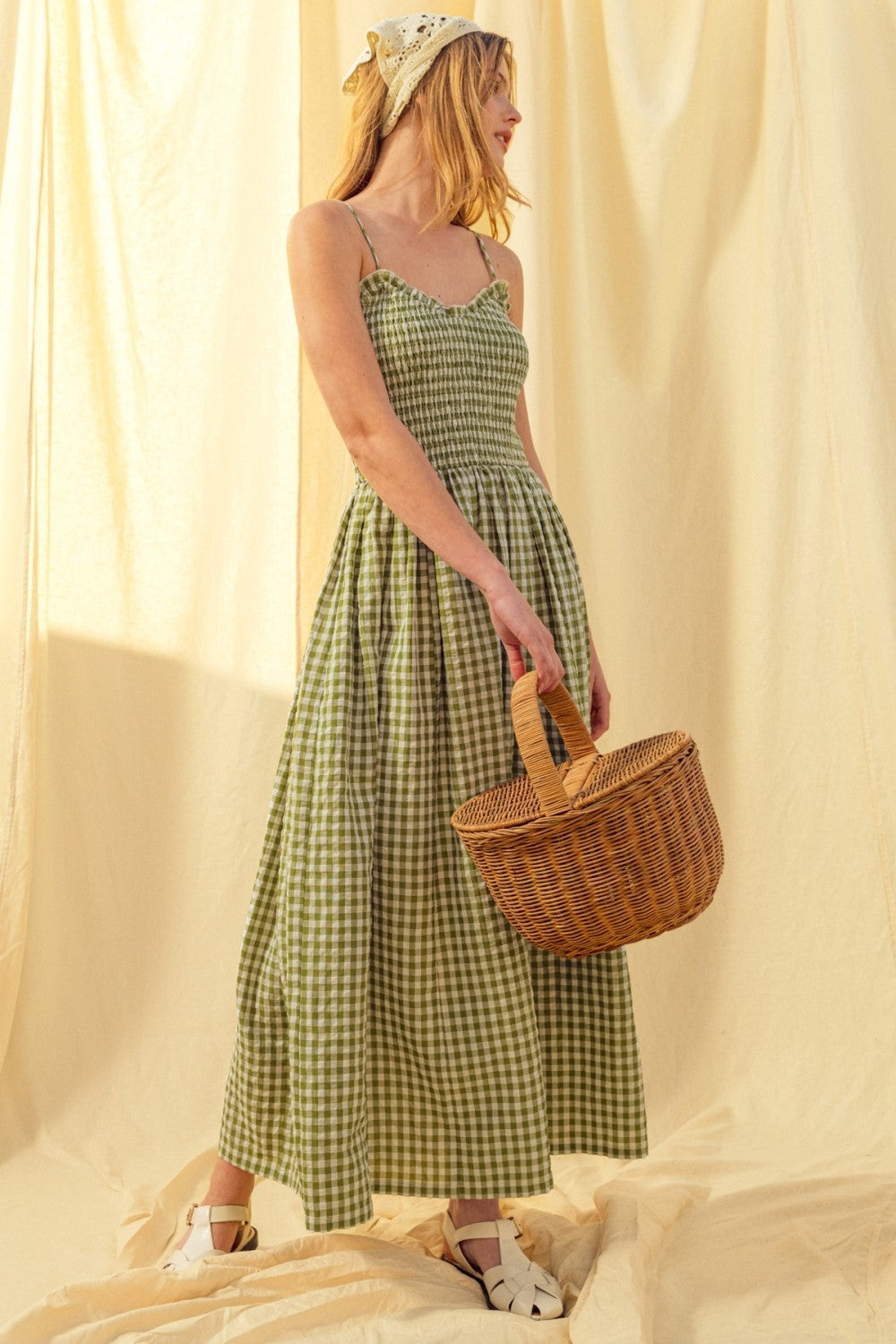 Woman in a Smocked cotton gingham maxi dress in green with spaghetti straps and flowing skirt