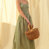 Woman in a Smocked cotton gingham maxi dress in green with spaghetti straps and flowing skirt