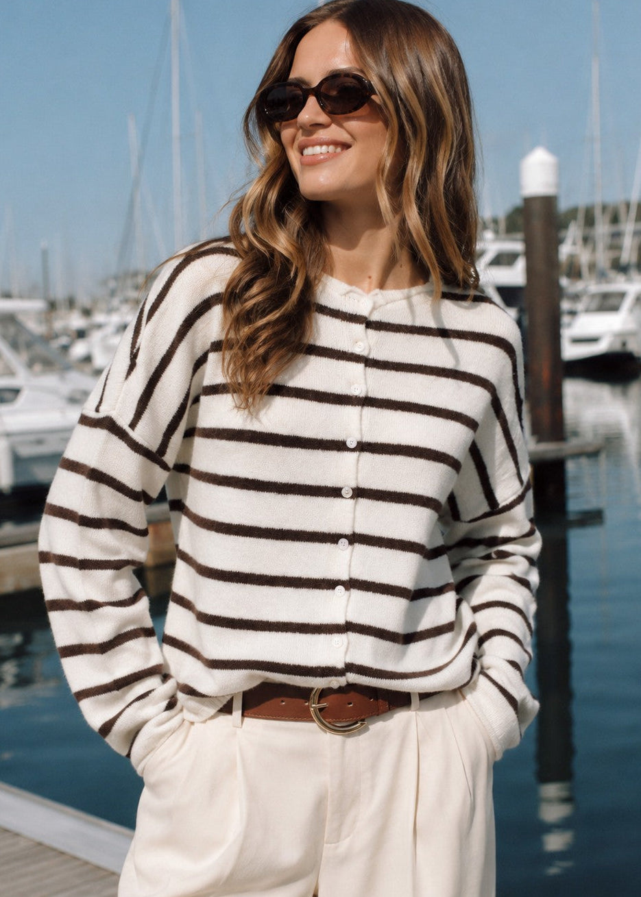 Model wearing the Things Between Piper Cardigan Cabana Stripe Cream Brown at a marina - lifestyle view