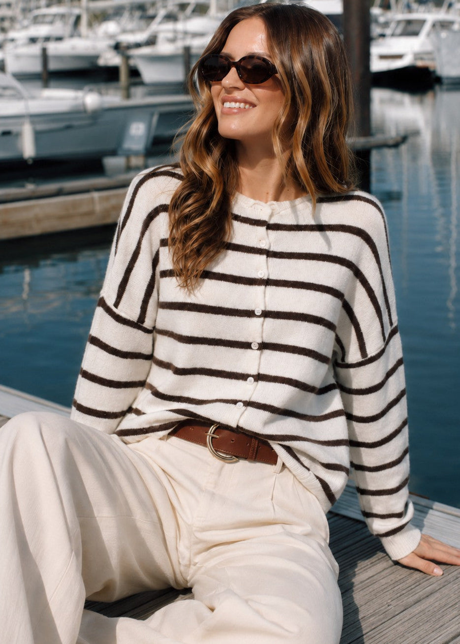 Model wearing the Things Between Piper Cardigan Cabana Stripe Cream Brown in a sitting lifestyle pose