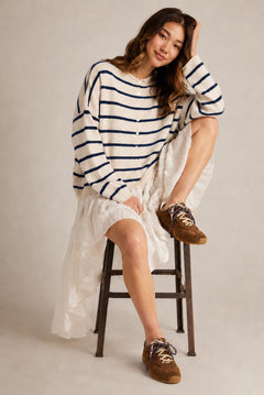Model wearing the Hailey Button Down Cardigan in Cabana Stripe Natural-Navy in a full outfit sitting pose