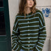 Model wearing the Things Between Piper Cardigan Cabana Stripe Olive Blue with light blue stripes and relaxed jeans