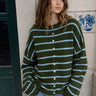 Model wearing the Things Between Piper Cardigan Cabana Stripe Olive Blue with light blue stripes and relaxed jeans