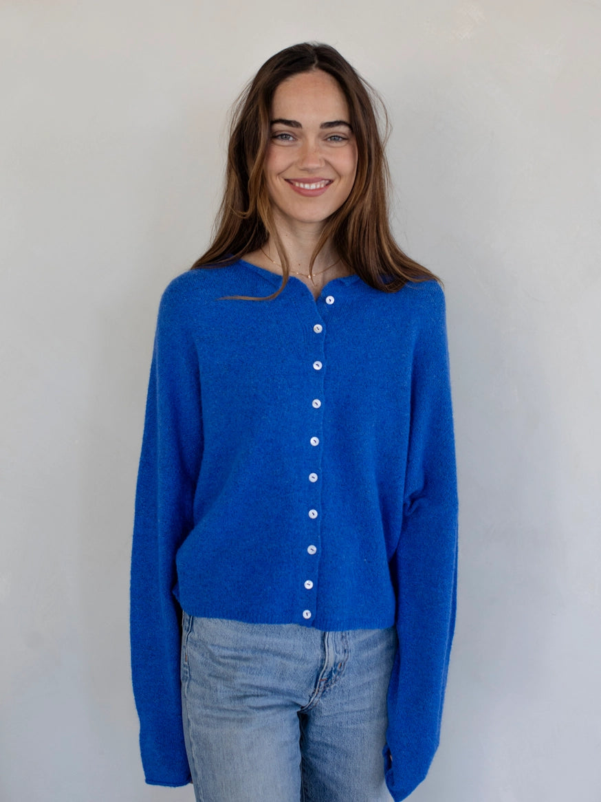 Woman wearing the Hailey Button Down Cardigan, also known as the Piper Cardigan, in blue — lightweight knit with button front.