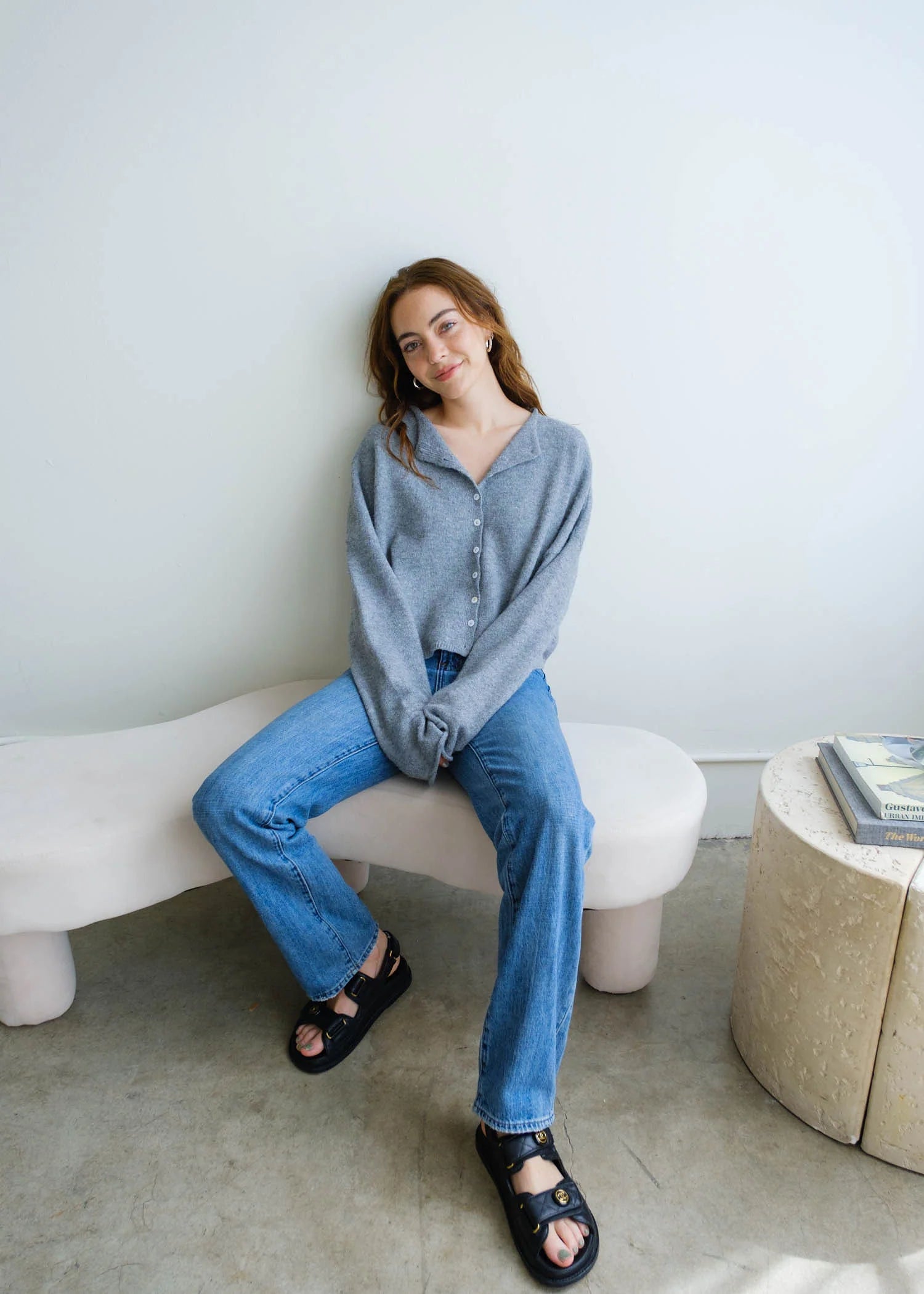 Lifestyle seated view of the Piper Cardigan in heather grey styled casually with denim