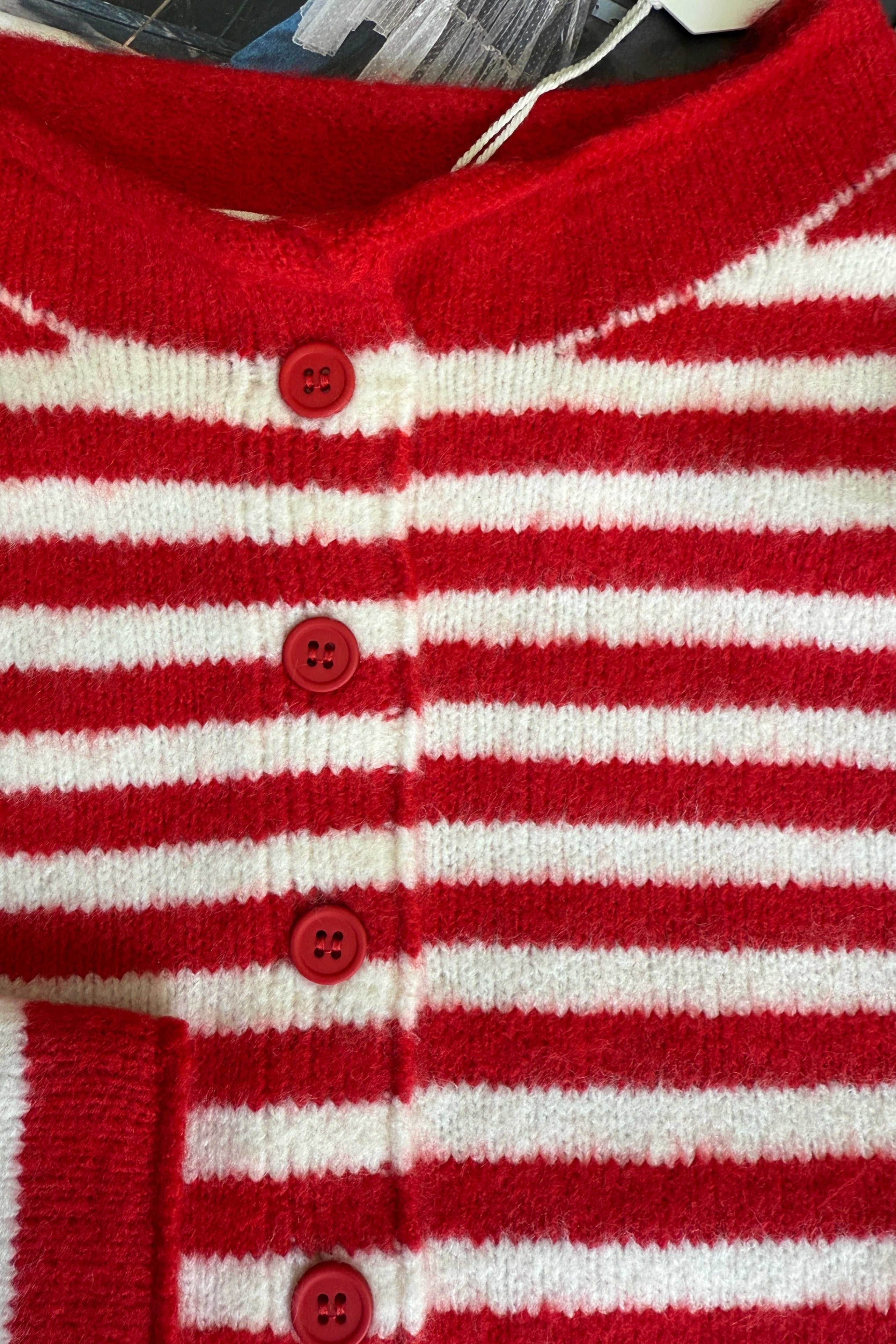 Red and white striped cardigan with buttons on a textured surface
