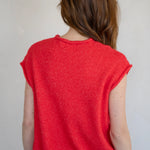 Person wearing a red sleeveless sweater against a plain background