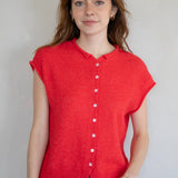 Woman wearing a red sleeveless button-up shirt against a plain background