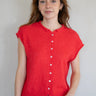 Woman wearing a red sleeveless button-up shirt against a plain background