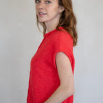 Woman wearing a red sleeveless Piper Vest Cardigan against a plain background