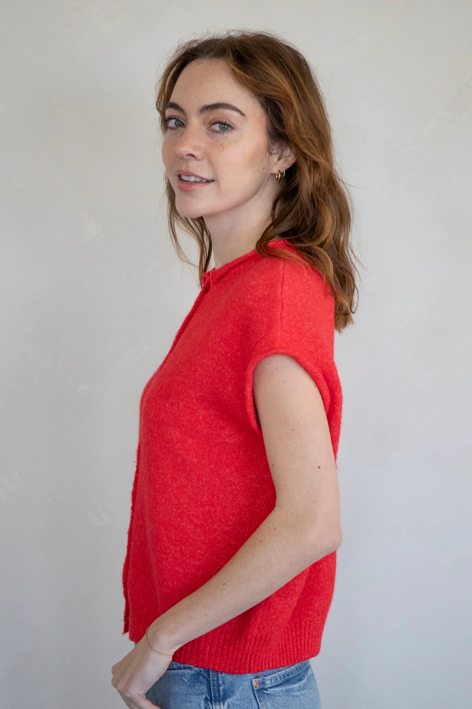 Woman wearing a red sleeveless Piper Vest Cardigan against a plain background